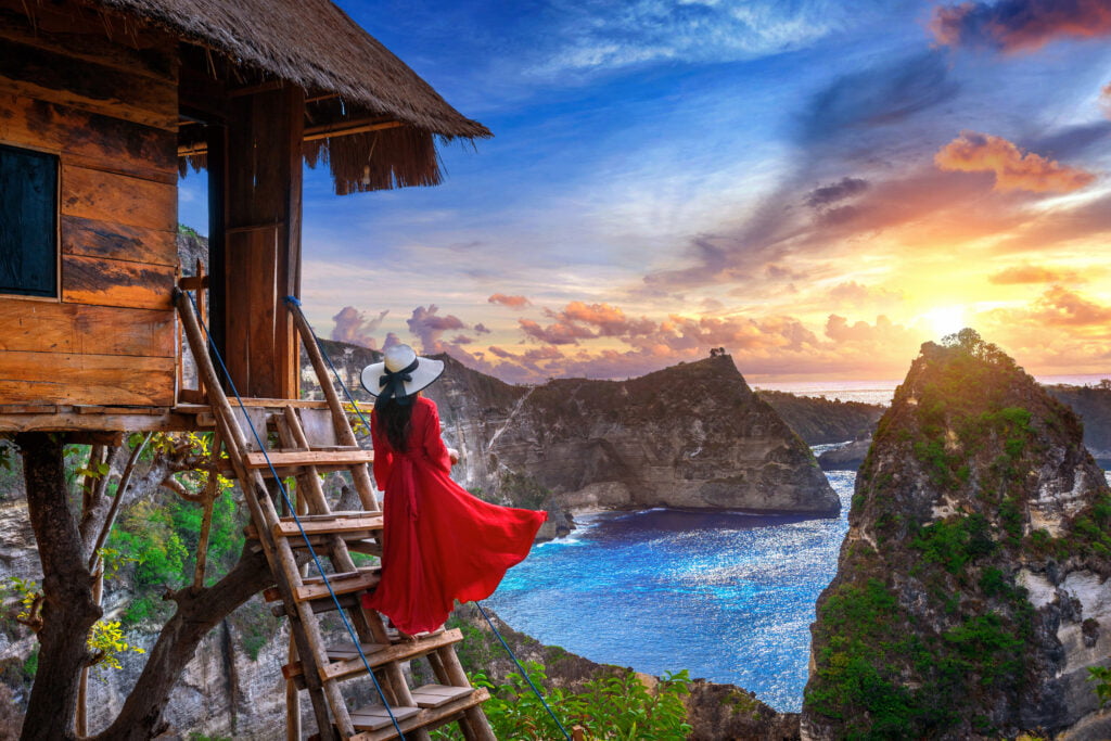 Young girl on steps of house on tree at sunrise in Nusa Penida i